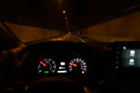 View from inside of a car driving in a big straight line tunnel at night. Stock Photos