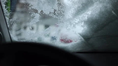 View from inside car, hand clears fresh snow outside windshield Video stock 325688156