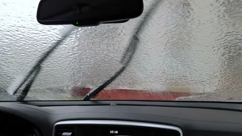 View from inside car on icy windshield. Spraying of non-freezing fluid and Stock Footage 221732025