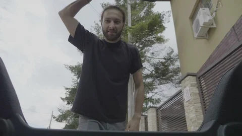 View from inside car of joyful young casual man loading heavy luggage in the Stock Footage 102440240