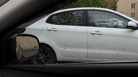 View from inside a car looking at a parked white vehicle heavily covered in Stock Photos