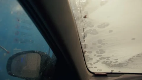 View from inside a car of a man spraying a solution on the windows of his car Stock Footage 316415809