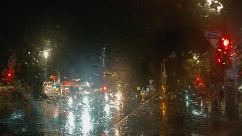 View from inside a car on a rainy night. Raindrops on the windshield blur city Stock Footage 346472230
