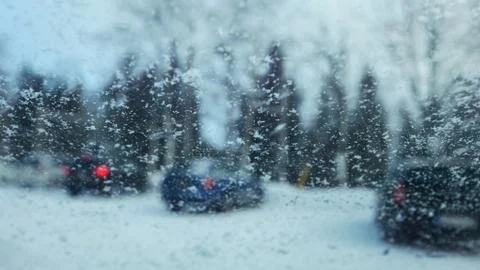View from inside car to snow flakes on windshield with blurred cars Foto stock