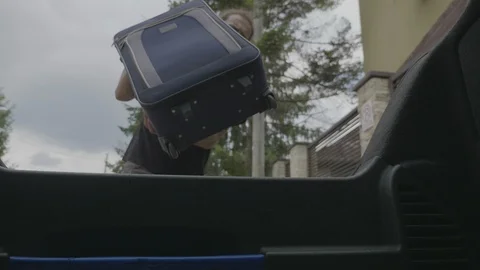 View from inside car trunk of millennial man loading travel bags in the boot  Stock Footage 102439954