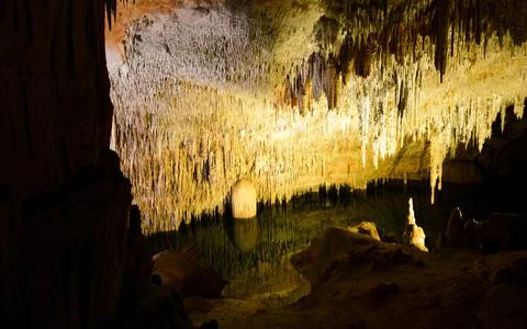 View inside of cave with stalactites and pool of water Stock Photos