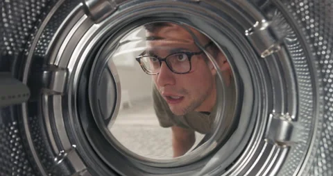 View from inside the drum, a man has bought a new washing machine, looks at it Stockbeeldmateriaal 200851328