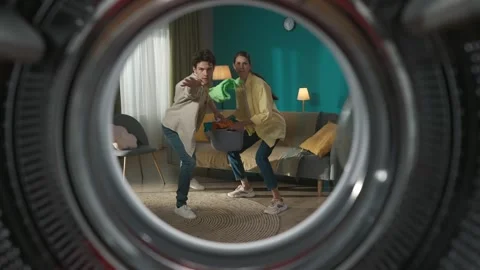 View from inside the empty washing machine young couple with laundry basket Stock Footage 247465939