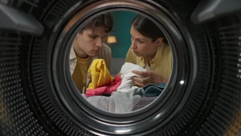 View from inside the empty washing machine, woman teaches her man how to use the Stock Footage 247467714