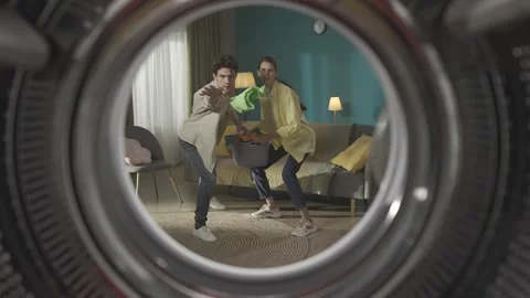 View from inside the empty washing machine young couple with laundry basket Stock Footage 247484888