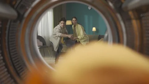 View from inside the empty washing machine young couple with laundry basket Stock Footage 247488962