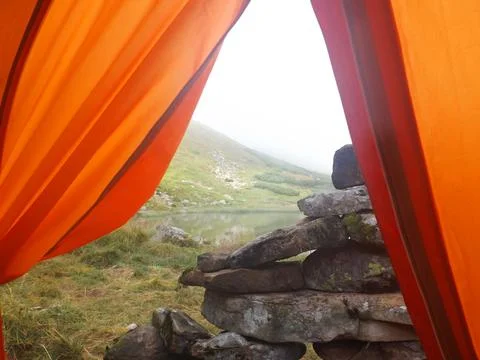 View From Inside Orange Tent On Mountain Lake And Stacked Rocks 스톡 사진