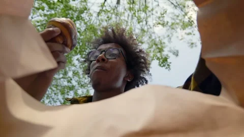 View from inside paper bag of African-American man take croissant and bite Stock Footage 244510963
