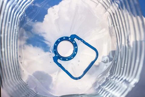 A view from inside a plastic bottle of a white cloud and a blue sky in the bl Stock Photos