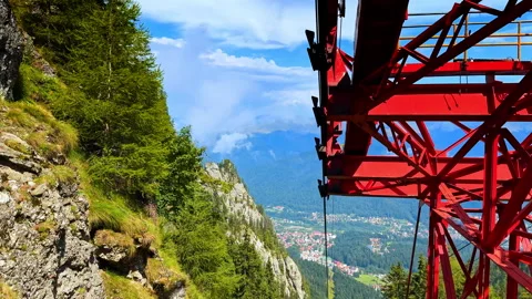 View from inside a red cable car gondola. The metal structure frames a steep Stock Footage 321538938