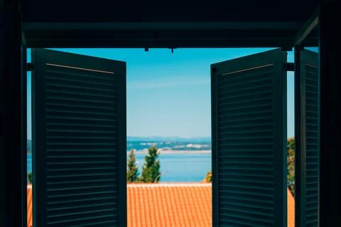 View from inside a room looking through open white louvered shutters toward.. Stock Photos