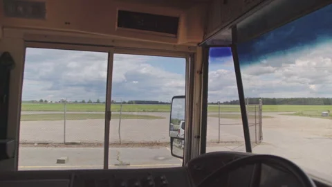 View from inside a school bus past the open front door to an empty parking lot Video stock 347731605