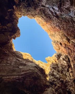 A view from inside a sea cave, looking out at the blue water and the rocky Stock Photos