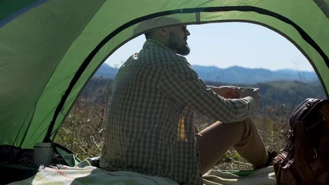 View from inside tent on bearded hiker young tourist traveler man enjoying Stock Footage 121524237