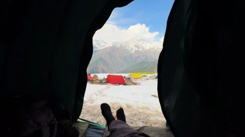 View from inside tent overlooking snowy campsite with colorful tents and Vidéo 334319392