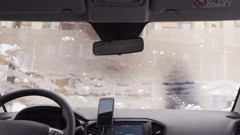 View inside through the windshield of the car - man cleans the car from the snow Vidéo 104823600