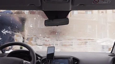 View inside through the windshield of the car - man cleans the car from the snow Vidéo 104823693