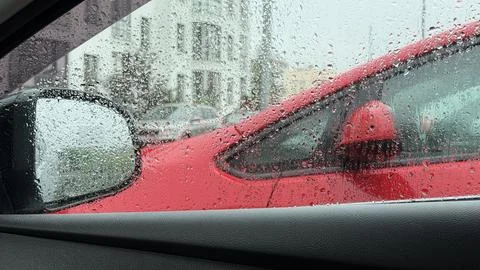 View from inside a vehicle through a wet window covered in raindrops, showing a Stock Photos