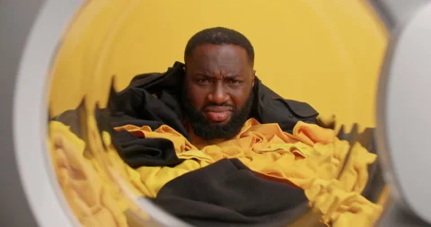 View from inside of washing machine. Displeased dark skinned man doesnt want to Stock Footage 156228172