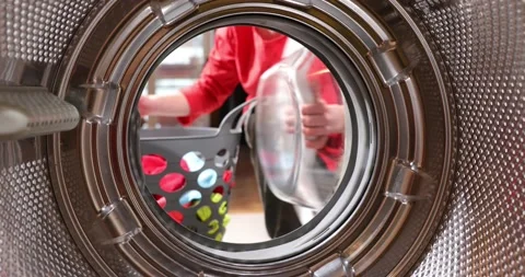 View from inside the washing machine drum. Young man is loading laundry in wa Stock Footage 152857332