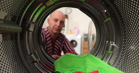 View from inside a washing machine, a man puts a colored wash into the washing Stock Footage 222797846