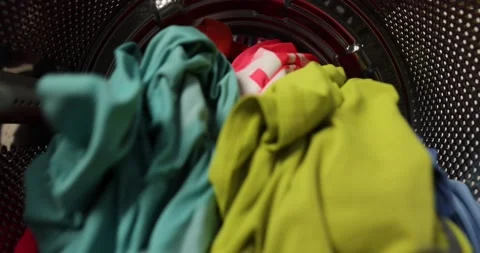 View from inside a washing machine, a man puts a colored wash into the washing Stock Footage 224083681