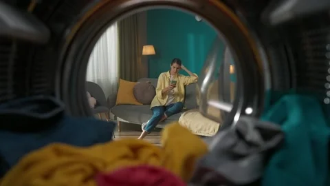 View from inside the washing machine, young woman sitting on the couch with Stock Footage 247466064