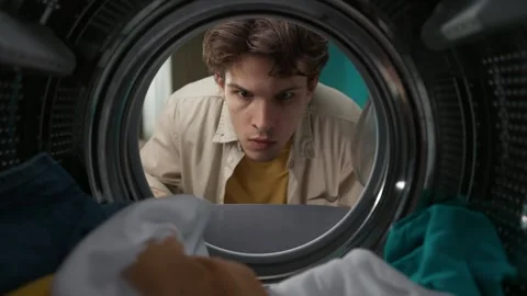 View from inside the washing machine, young man with laundry basket takes out Stock Footage 247466489