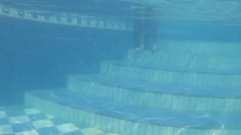 View from inside the water of a man entering the pool in a meeting with friends Stockbeeldmateriaal 170023983