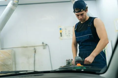 View from interior of car through windshield of mechanic male polish auto hood Stock Photos