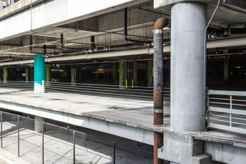 View into interior of an empty parking garage with pipes and chain link fence Stock Photos