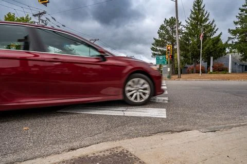 View of a intersection crosswalk as a motion blurred vehicle does a right turn Foto stock