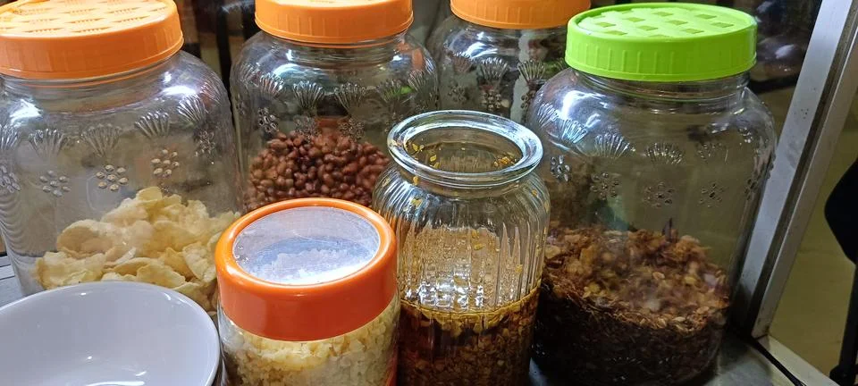 View of jars containing toppings and condiments for savory porridge Stock Photos