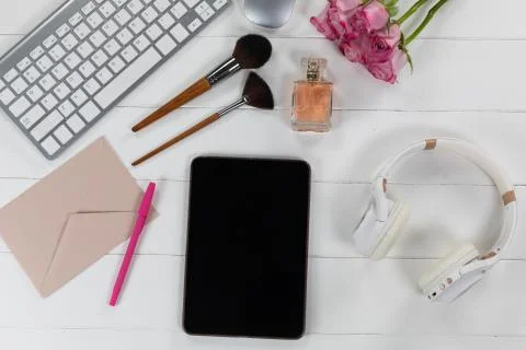 View of a keyword and make up with tablet and perfume on white wood table Photos