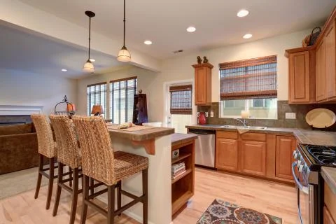 View of kitchen interior with hardwood storage combination, bar and pendant l Stock Photos