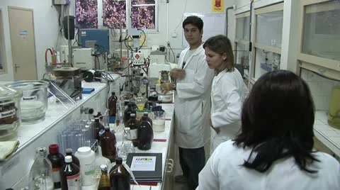 View of Laboratory Work Table with Many Containers As Three Workers Talk 스톡 동영상 18968081