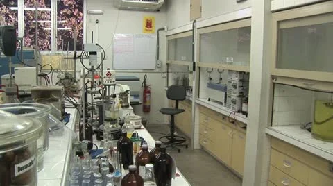 View of Laboratory Work Table with Many Containers As Two Workers Walk Through Stock Footage 20441790