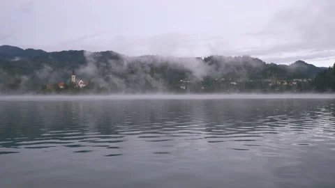 View of lake Bled and Bled island under fog and mist in early morning, Bled Stock Footage 135495112