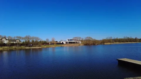 View of a lake with clear blue sky and modern building under bright sunlight on Video stock 332636685