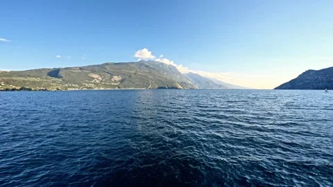 View of Lake Garda with the mountains in the background under a blue sky Stock Footage 346131799