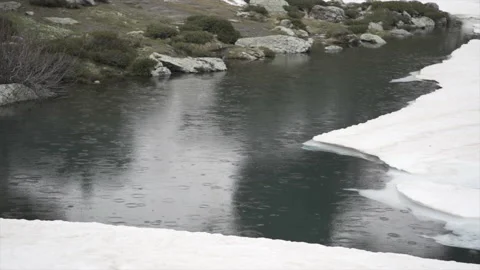 View of a lake in the middle of a mountain as raindrops fall Stock Footage 221515305