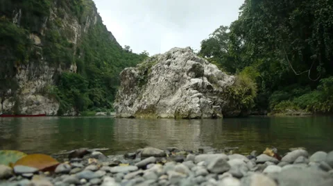 View from a lake shore: a stone set in the middle of tranquil water, with trees  Stock Footage 32720254