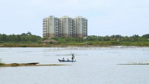 View of a lake with a small boat, high-rise building in the background Stock Footage 220733146