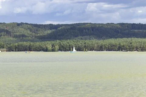 View of the lake surface, hills, clouds in windy weather with one yacht Stock Photos