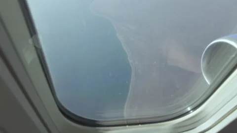 View of the land and the ocean from the window of the plane, the sun is Stock Footage 236421109